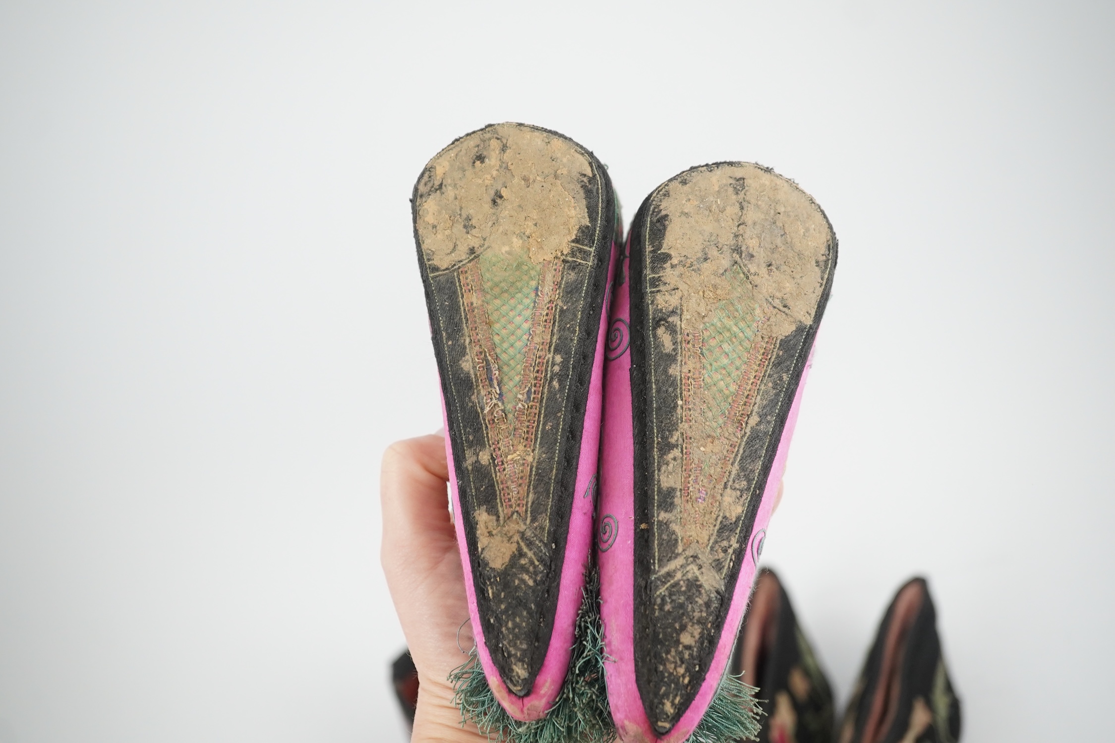 Four pairs of late 19th / early 20th Chinese ladies bound foot shoes, made in various coloured silks, with colourful floral embroidered motifs, two pairs with decorative silk pom-poms and another made of purple and black